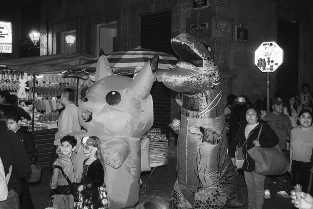 Black and white photo of people in inflatable costumes during a nighttime festival.